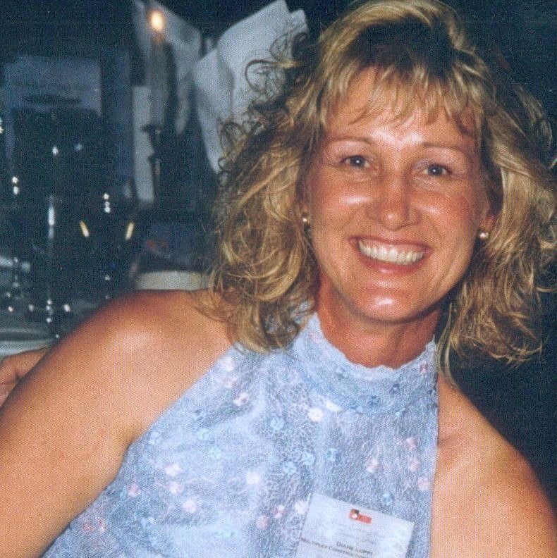 Smiling woman in a blue halter dress at a dimly lit event