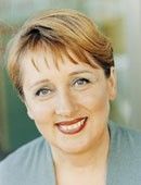 Smiling woman with short light brown hair against a soft green background