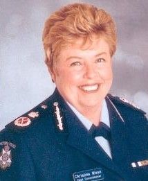 Portrait of a smiling uniformed officer in dark dress uniform against a gray backdrop