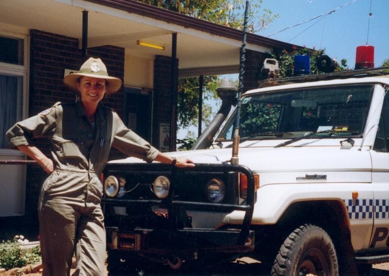Man leaning on a white 4x4 truck parked beside a house in bright sunlight