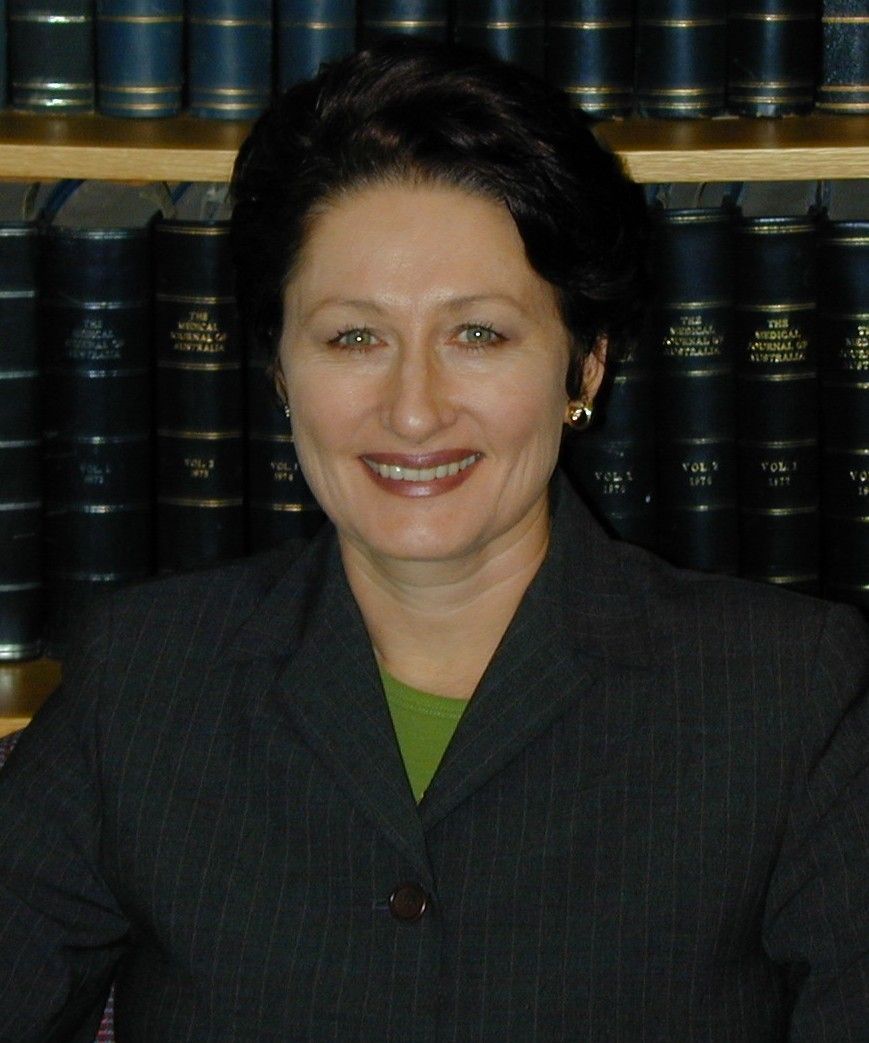 Smiling woman in a dark blazer in front of bookshelves