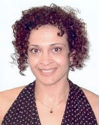 Portrait of a smiling person with short curly hair, wearing a black polka-dot top on a white background