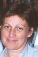 Close-up portrait of a person with short brown hair, wearing a light-colored top and a slight smile.