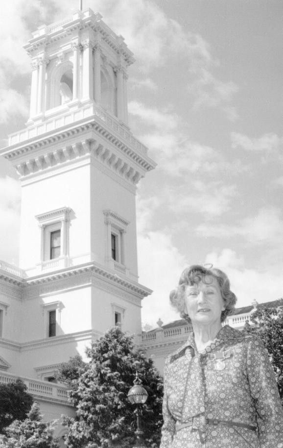 Woman standing in front of a tall historic tower under a cloudy sky