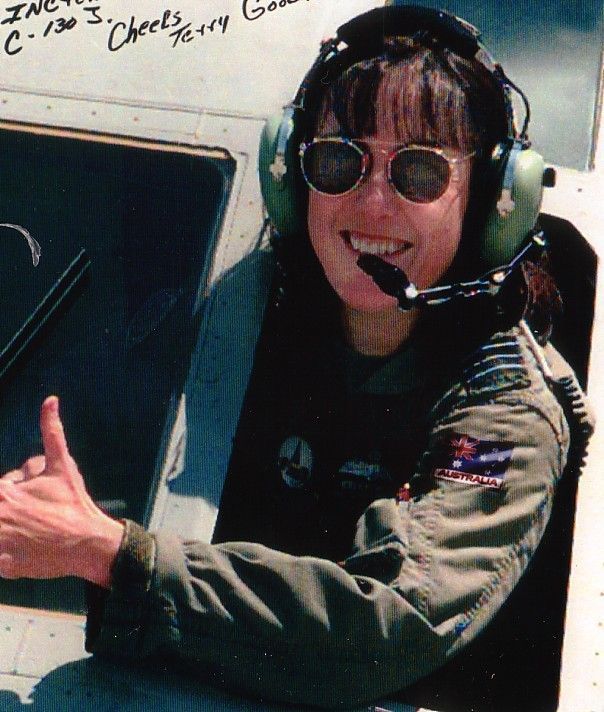 Smiling pilot wearing headset and sunglasses in an aircraft cockpit, giving a thumbs-up