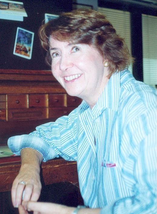 Smiling person in a blue striped shirt leaning on a bar counter in a dimly lit room