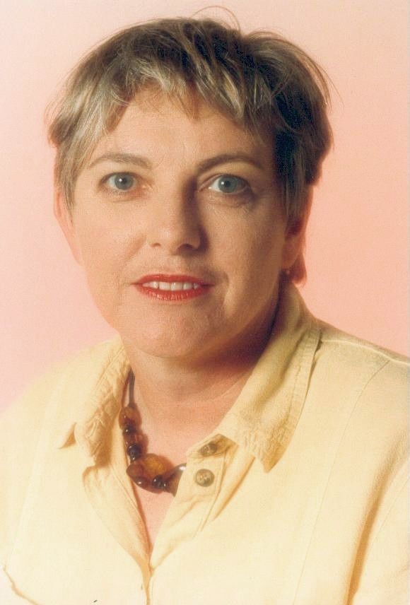 Portrait of a woman in a pale yellow blouse against a soft pink background