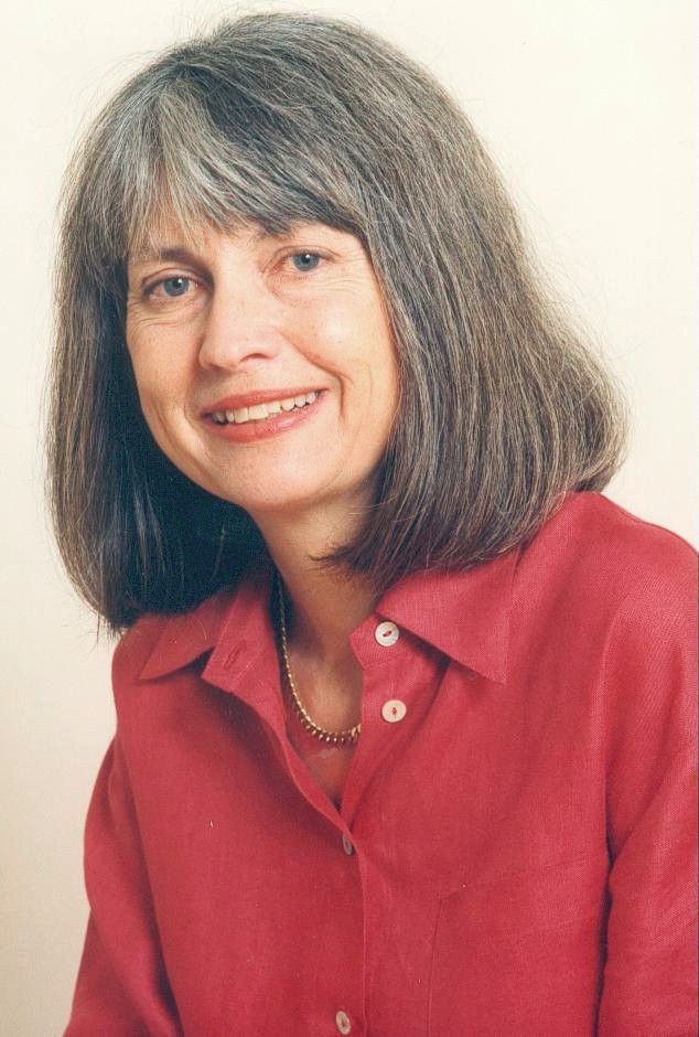Portrait of a smiling person with gray hair wearing a red shirt and necklace