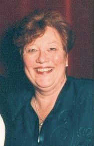 Smiling woman in a dark teal top against a maroon background