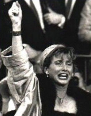 Woman cheering with raised fist, mouth open, in a black-and-white crowd scene