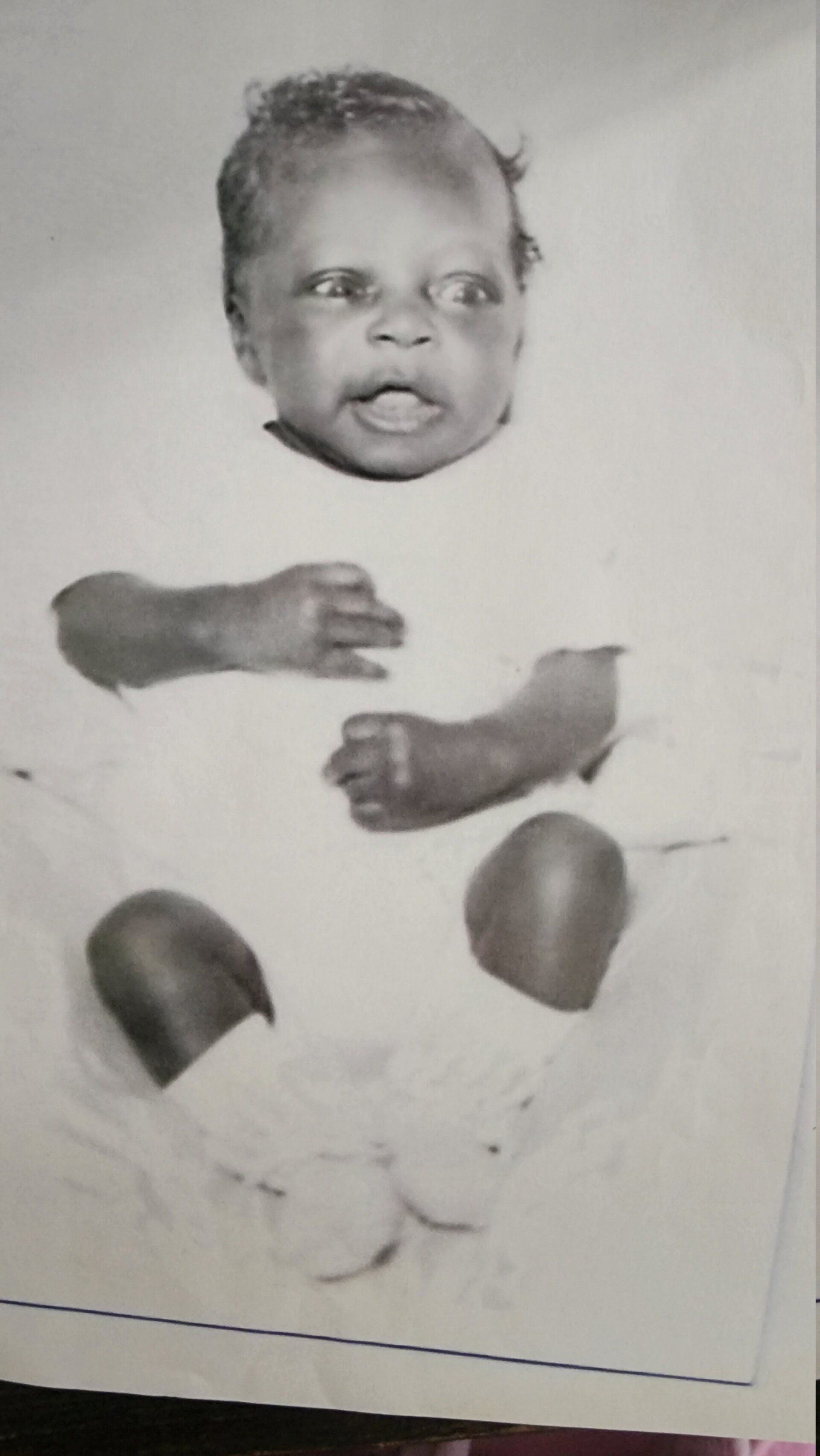Black-and-white photo of a baby with separate arms and legs, likely a printed cutout or collage.