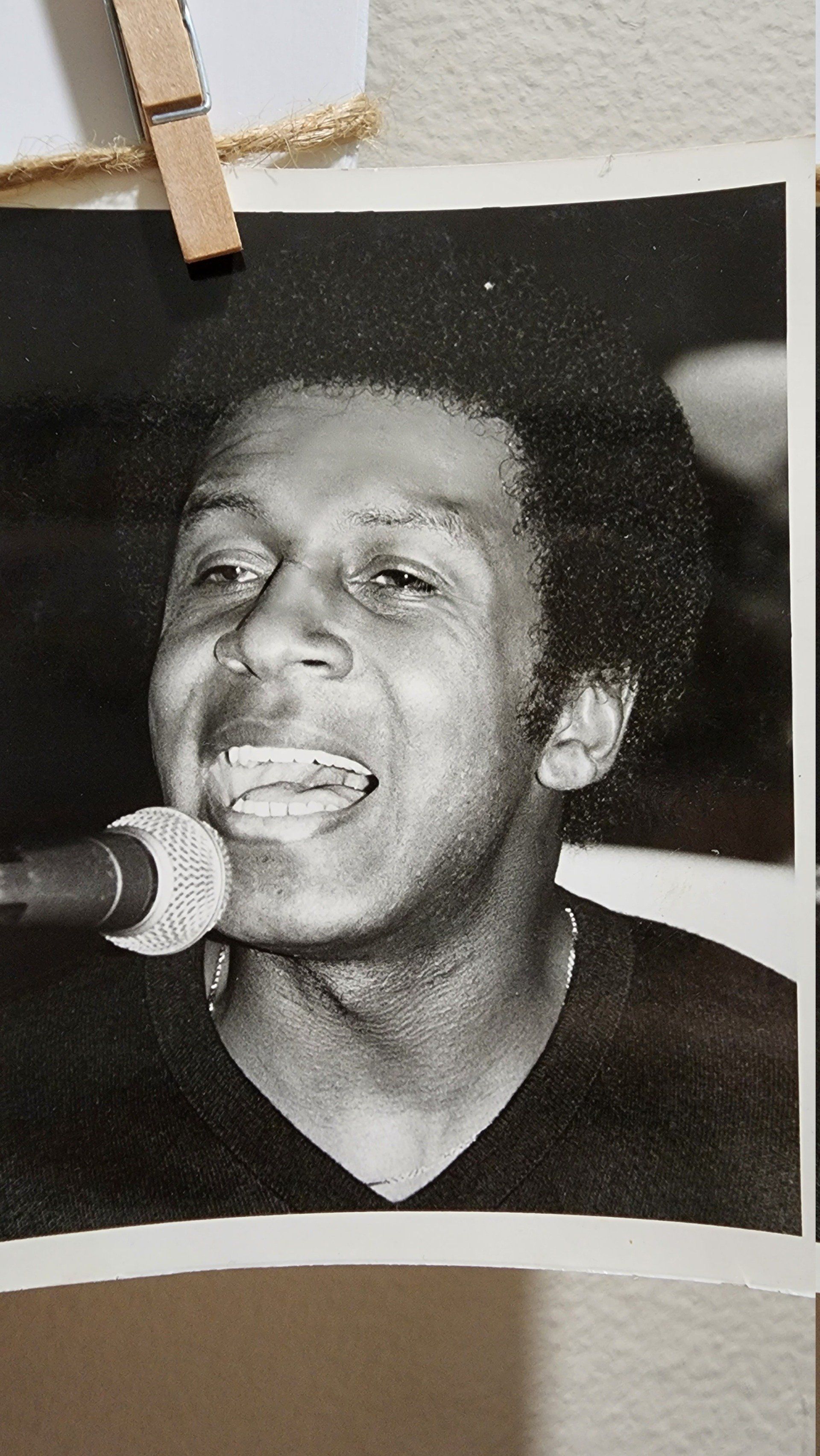 Black-and-white photo of a singer smiling into a microphone while performing