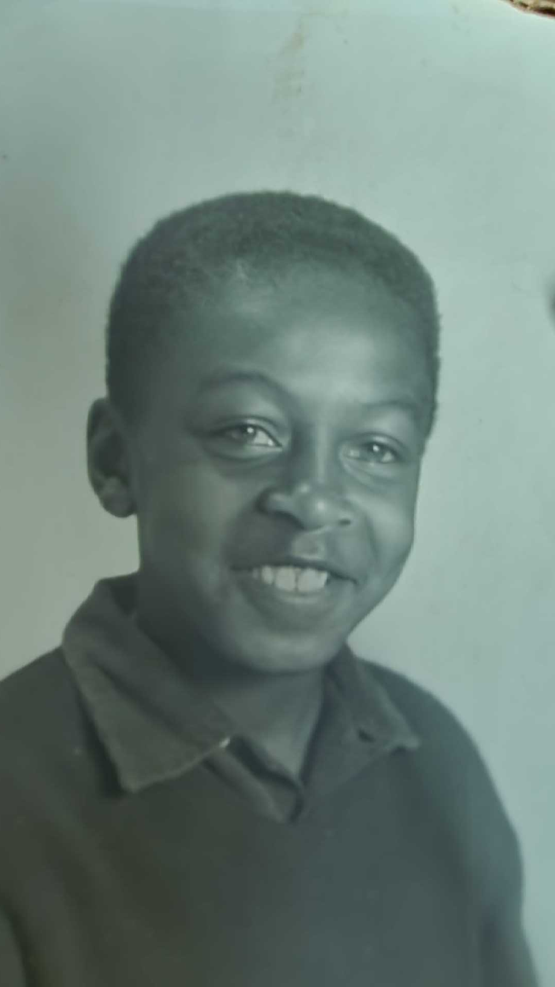 Smiling child in a dark polo shirt against a plain light background