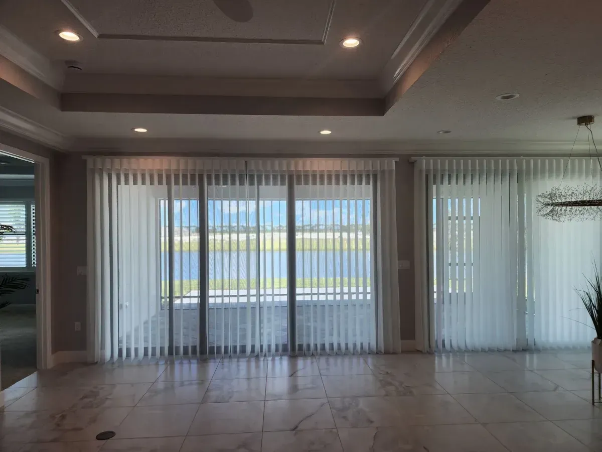 Empty modern living room with large sliding glass doors and vertical blinds