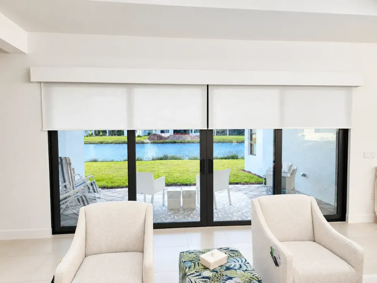Bright living room with two cream chairs, glass coffee table, and sliding doors opening to a patio and green yard