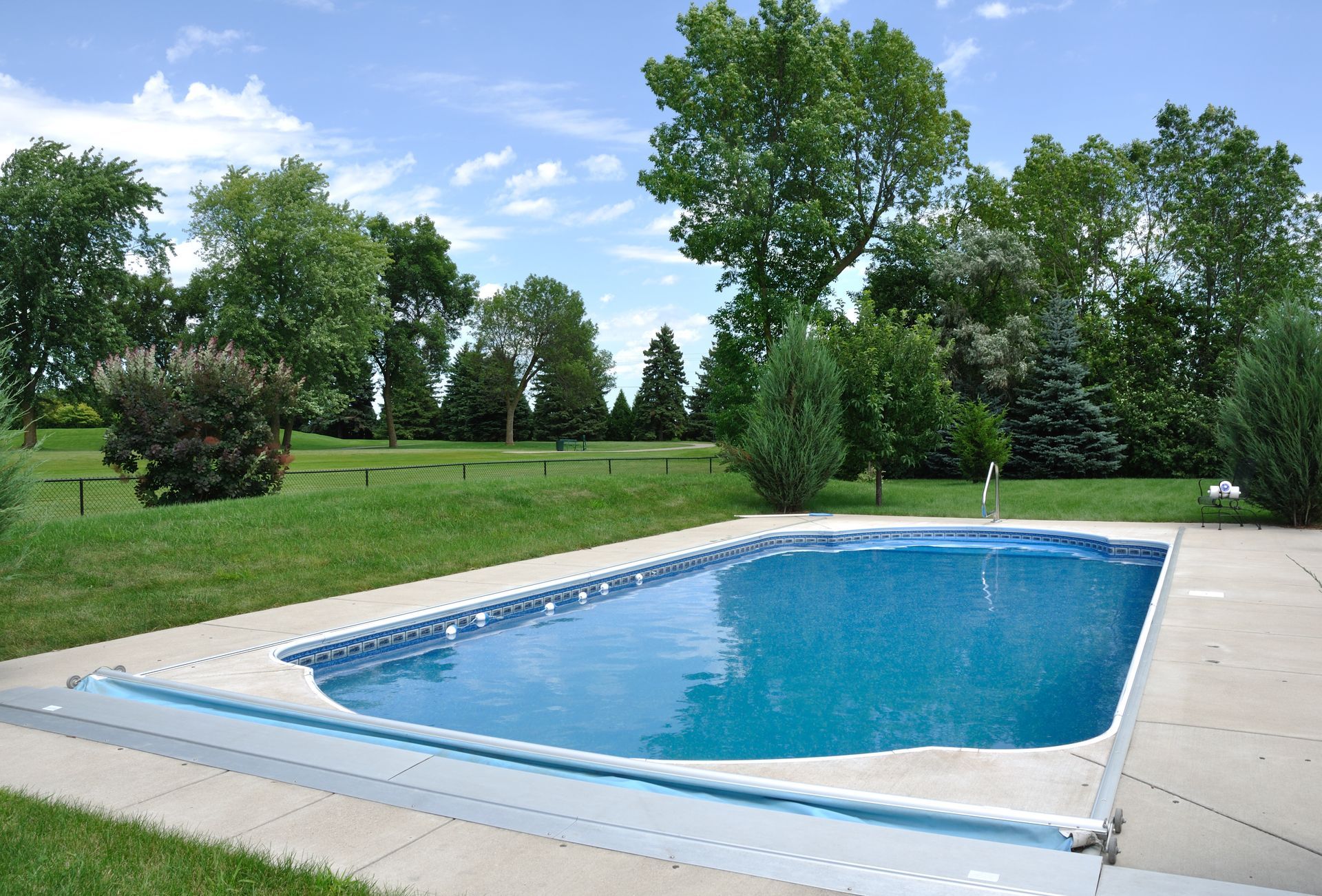 A large swimming pool surrounded by trees on a sunny day