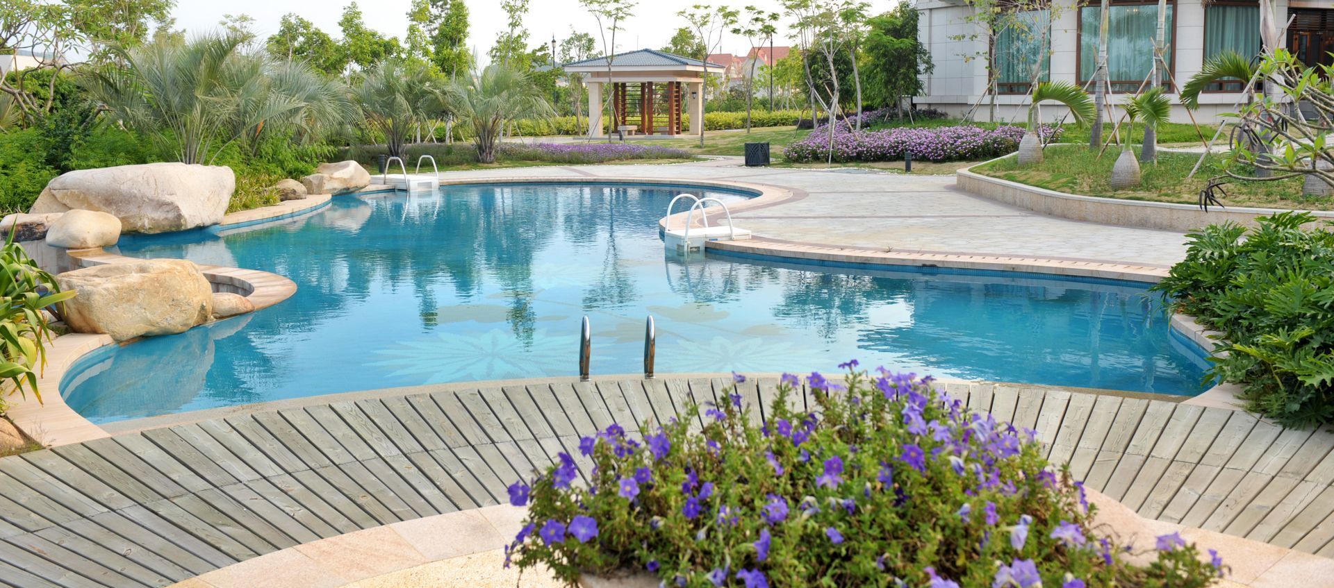 A large swimming pool with purple flowers in the foreground