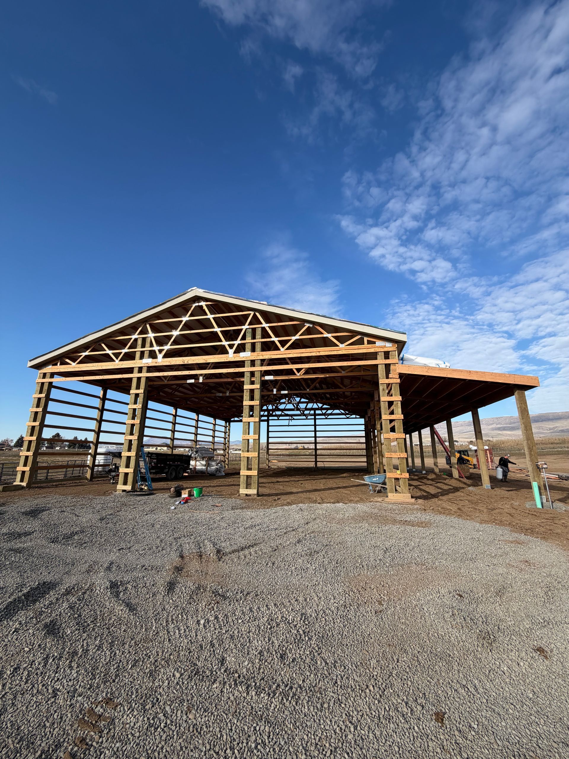 Construction site with wooden forms and strings outlining a rectangular area. Dirt, snow, and a green building are visible.