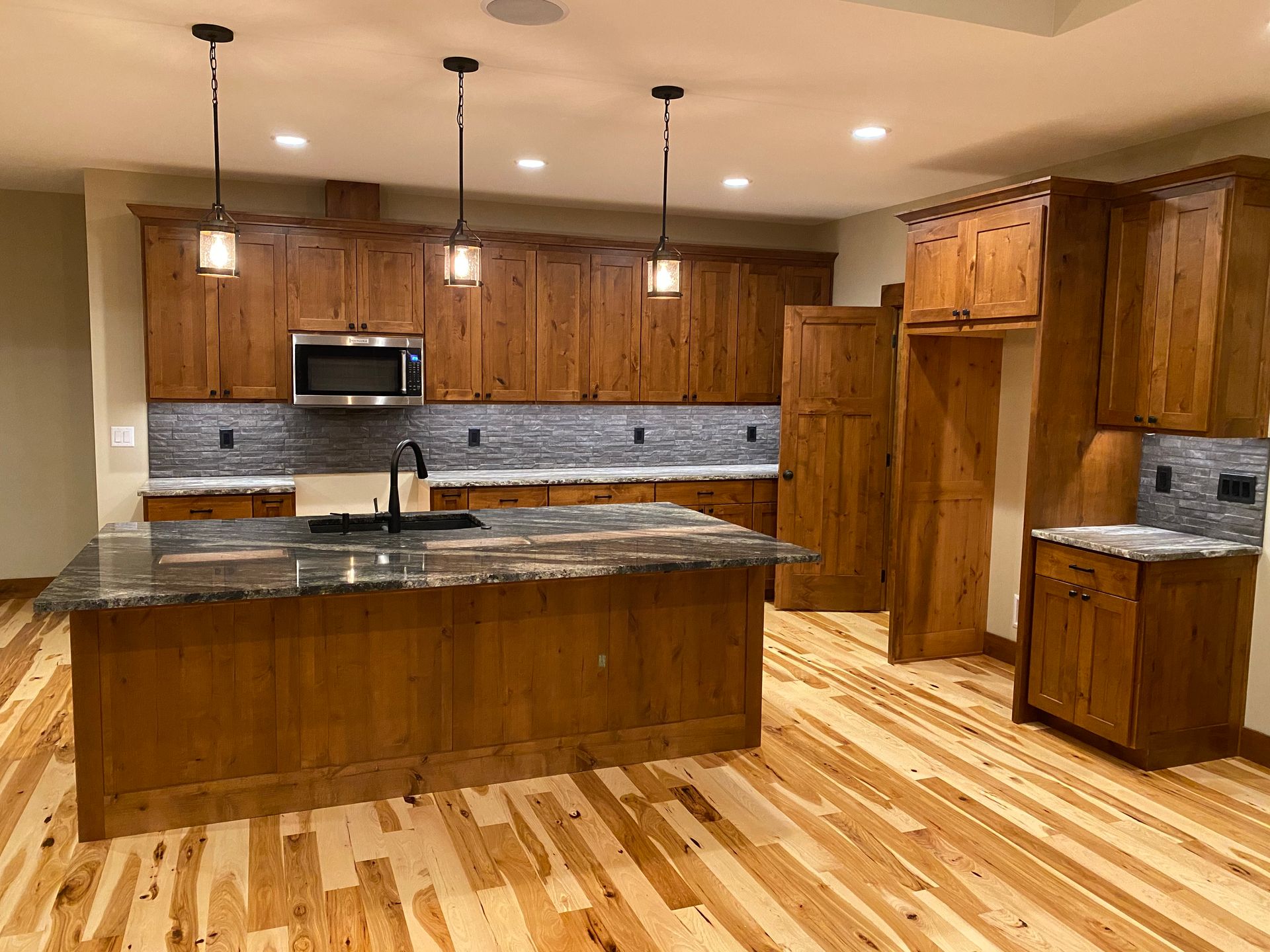 Spacious kitchen with wooden cabinets, granite island, stainless appliances, and light hardwood floors