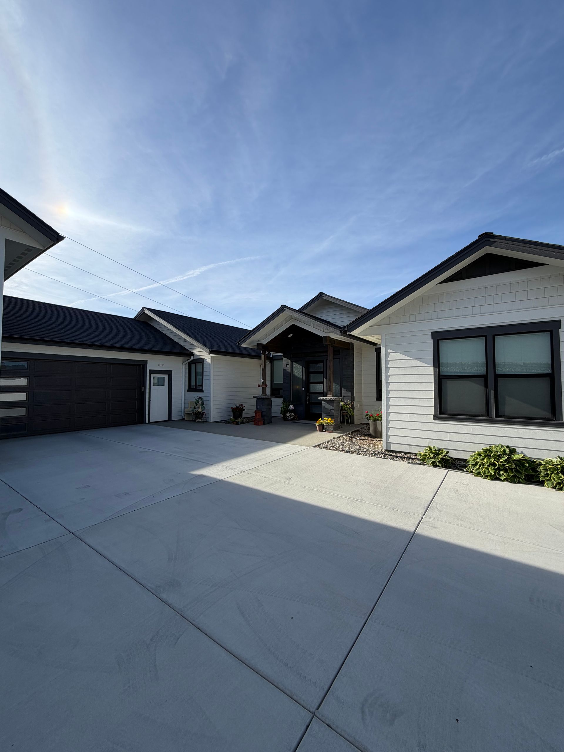 Modern suburban driveway with white houses and a bright blue sky