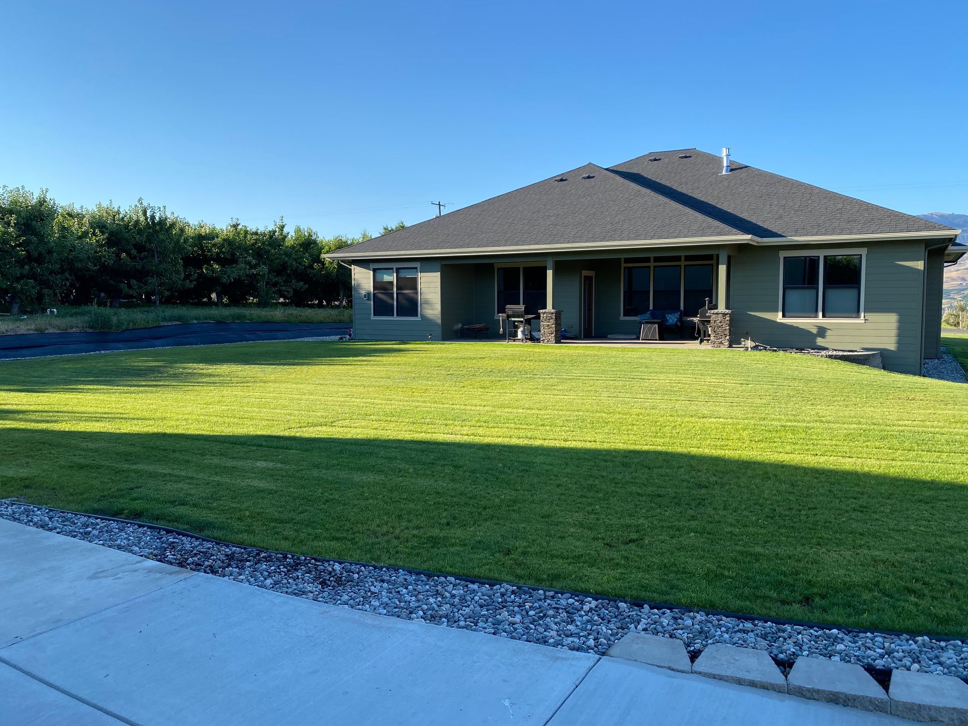 Suburban house with a large green lawn under a clear blue sky