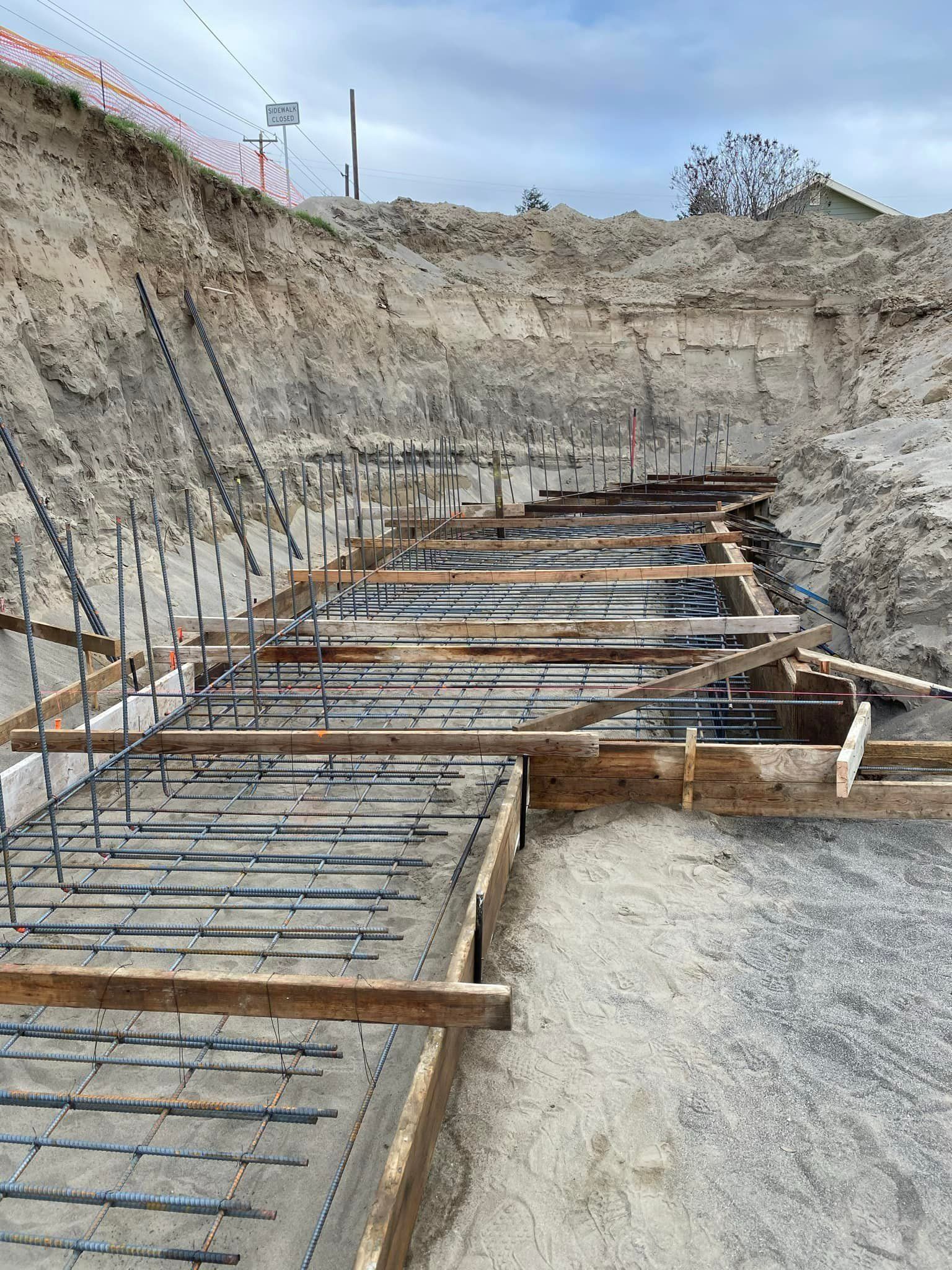 Construction site with forms and rebar for a concrete structure, within a deep excavation.
