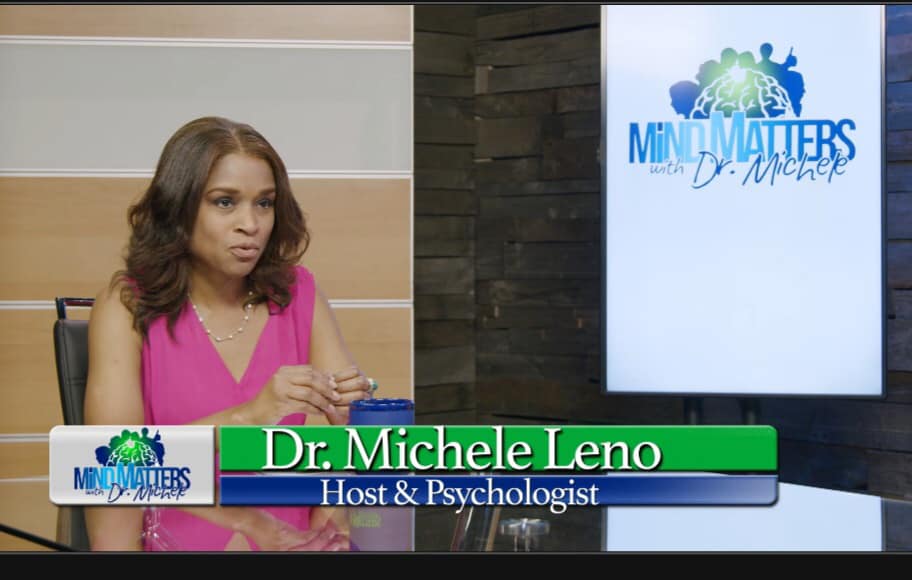 Woman in pink at studio desk, with “Mind Matters” screen and lower-third: Dr. Michele Leno, Host & Psychologist
