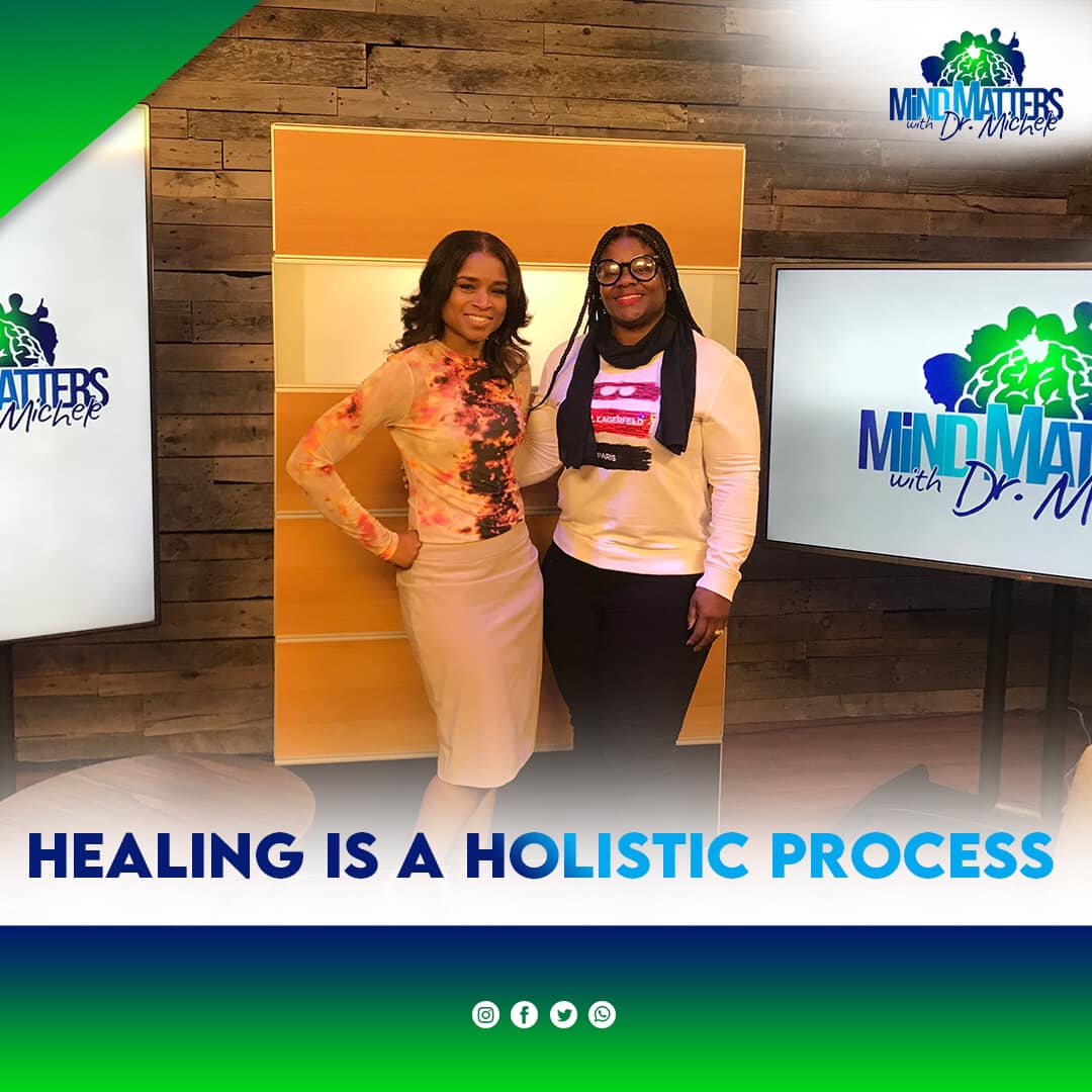 Two women posing at a Mind Matters event with banner reading “Healing is a Holistic Process.”