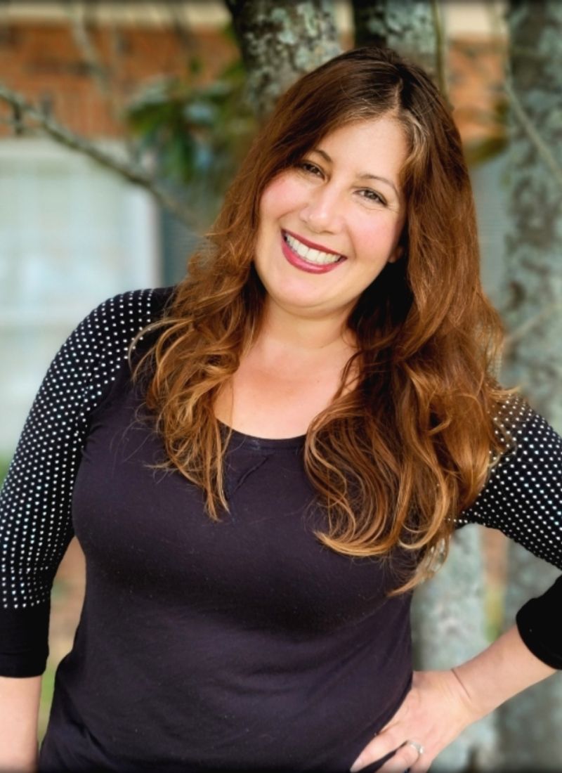 A woman in a black shirt with polka dot sleeves is smiling for the camera.