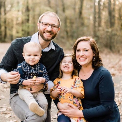 A family is posing for a picture in the woods.
