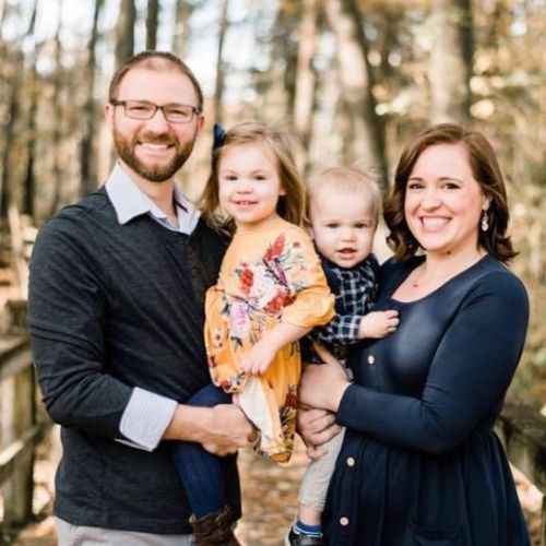 A family is posing for a picture in the woods.
