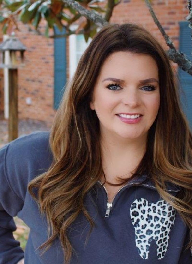 A woman wearing a sweater with a tooth on it