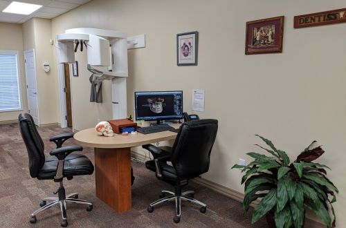 A dental office with a table and chairs and a computer.