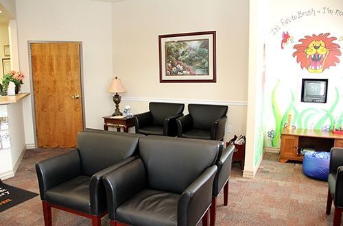 A waiting room with black chairs and a picture of a lion on the wall.