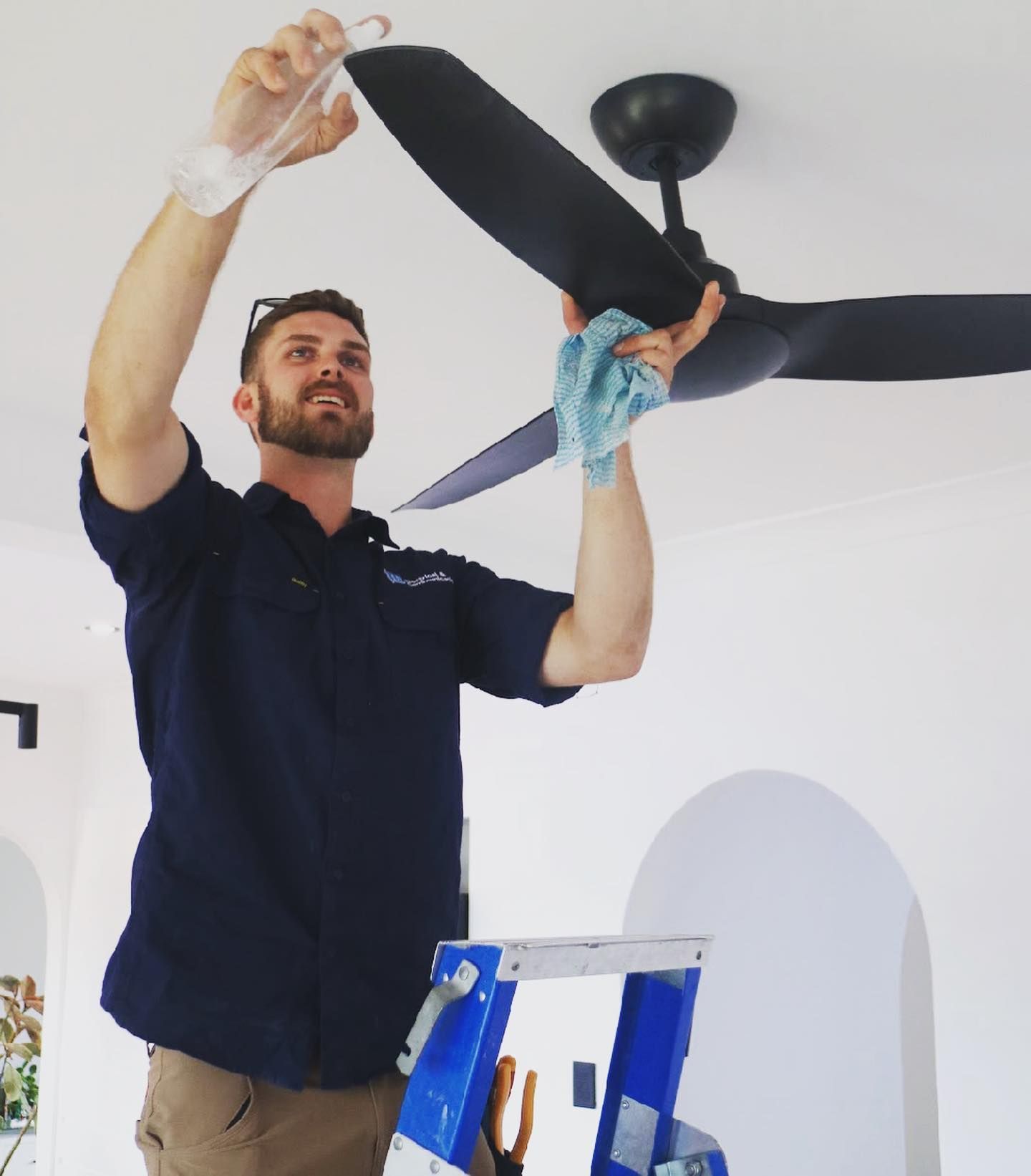 Electrician Finalising Ceiling Fan Fitting — TB Electrical & Communications in Erina, NSW
