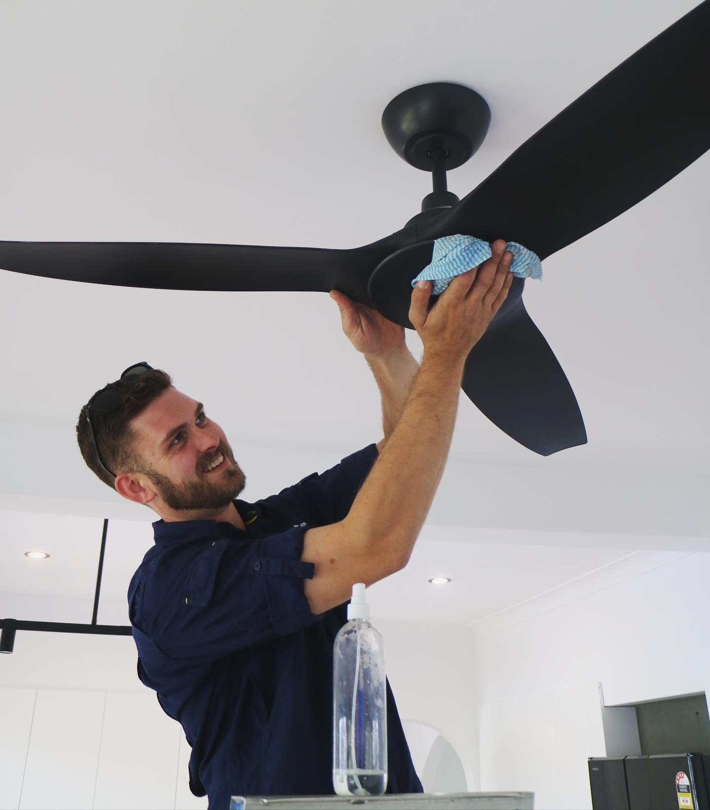 Electrician Finalising Ceiling Fan Installation — TB Electrical & Communications in West Gosford, NSW