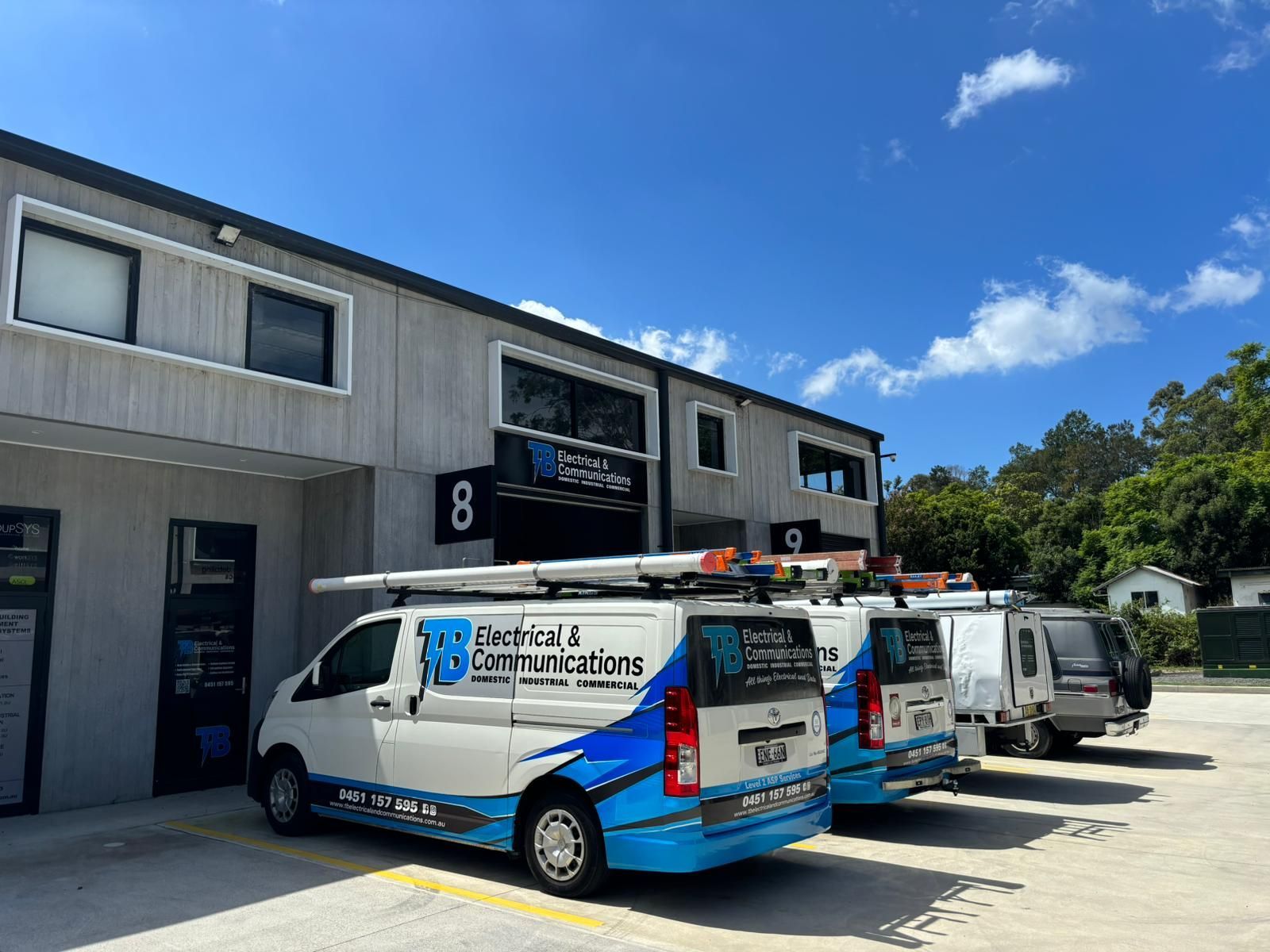 Work Vehicles Linned up Outside A Building — TB Electrical & Communications in West Gosford, NSW