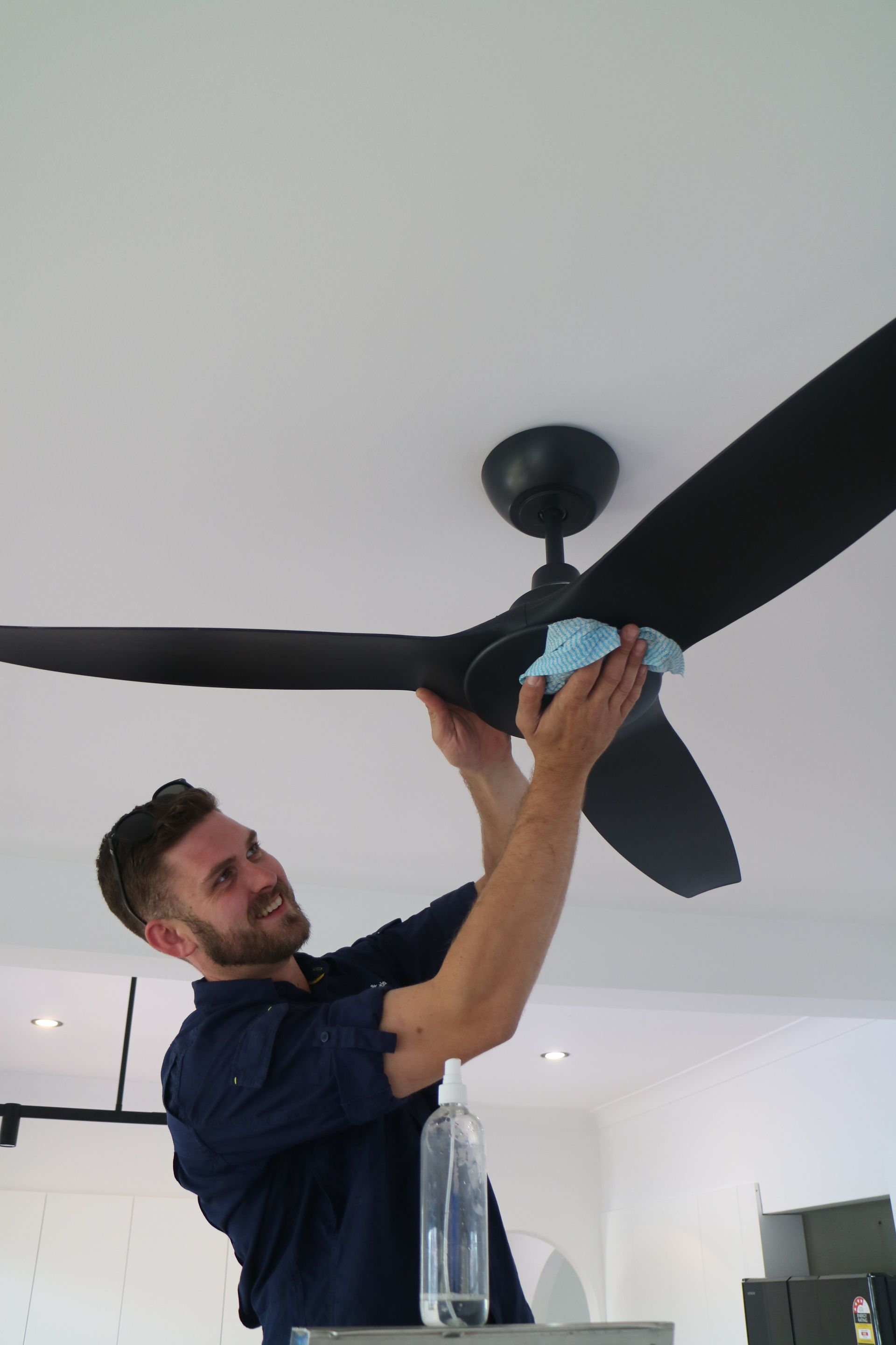 Electrician Cleaning A Ceiling Fan After Installation — TB Electrical & Communications in West Gosford, NSW
