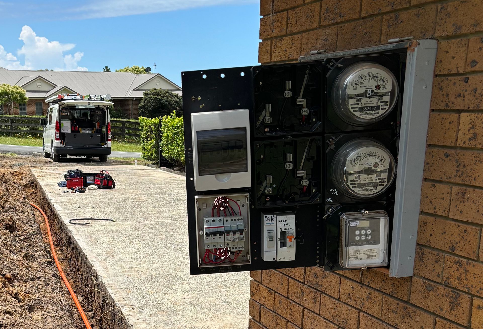 A Man is Working on an Electrical Panel With a Screwdriver — TB Electrical & Communications in West Gosford, NSW