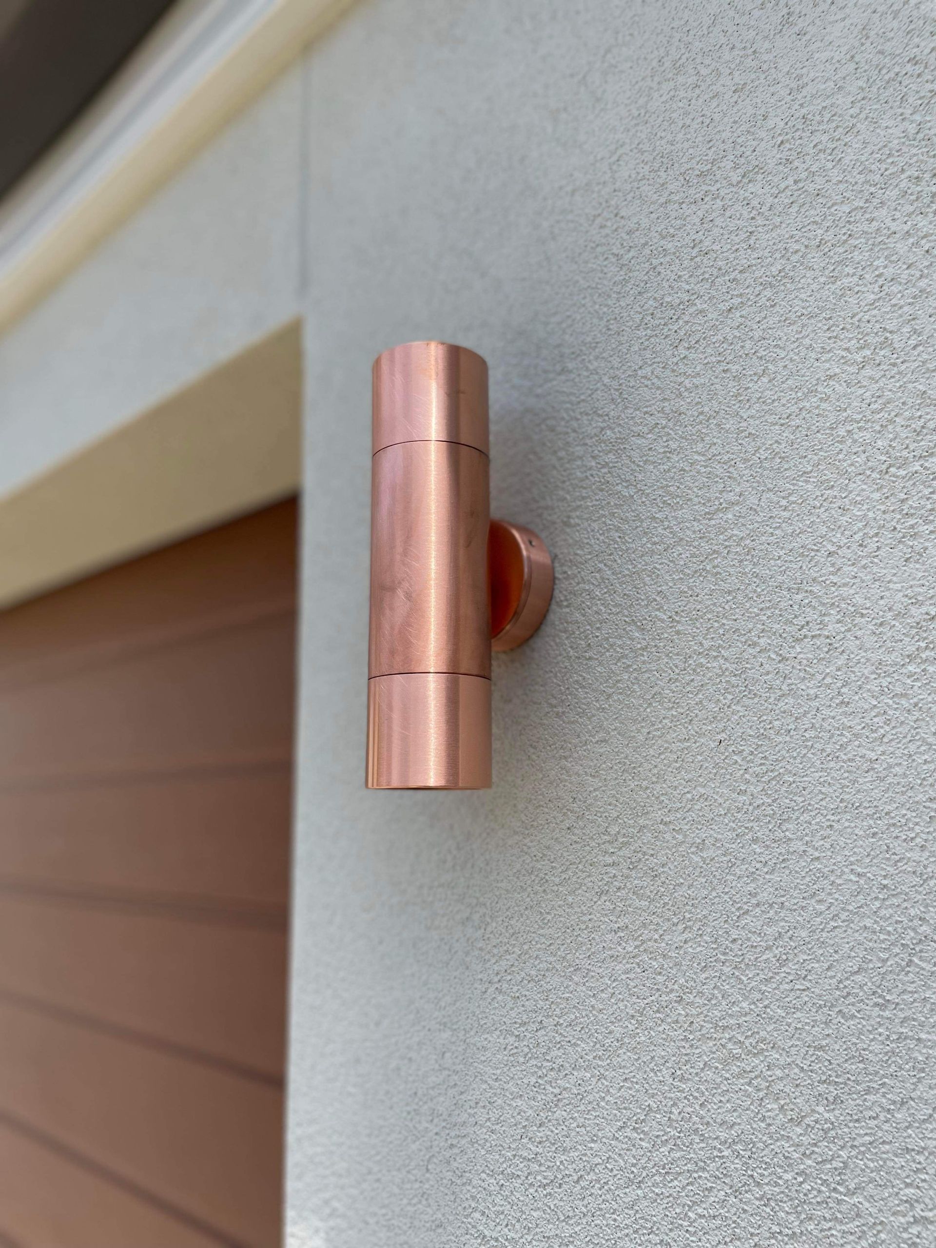 An Outdoor Light Fixture On A Garage Wall In Copper — TB Electrical & Communications in West Gosford, NSW