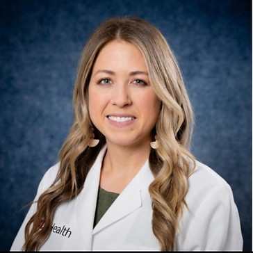 Headshot of a healthcare professional in a white coat with a blue background.