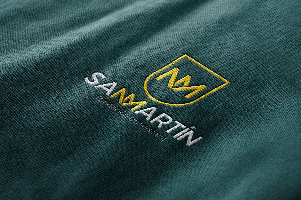 Un primer plano de una camisa verde con un logotipo bordado en ella.