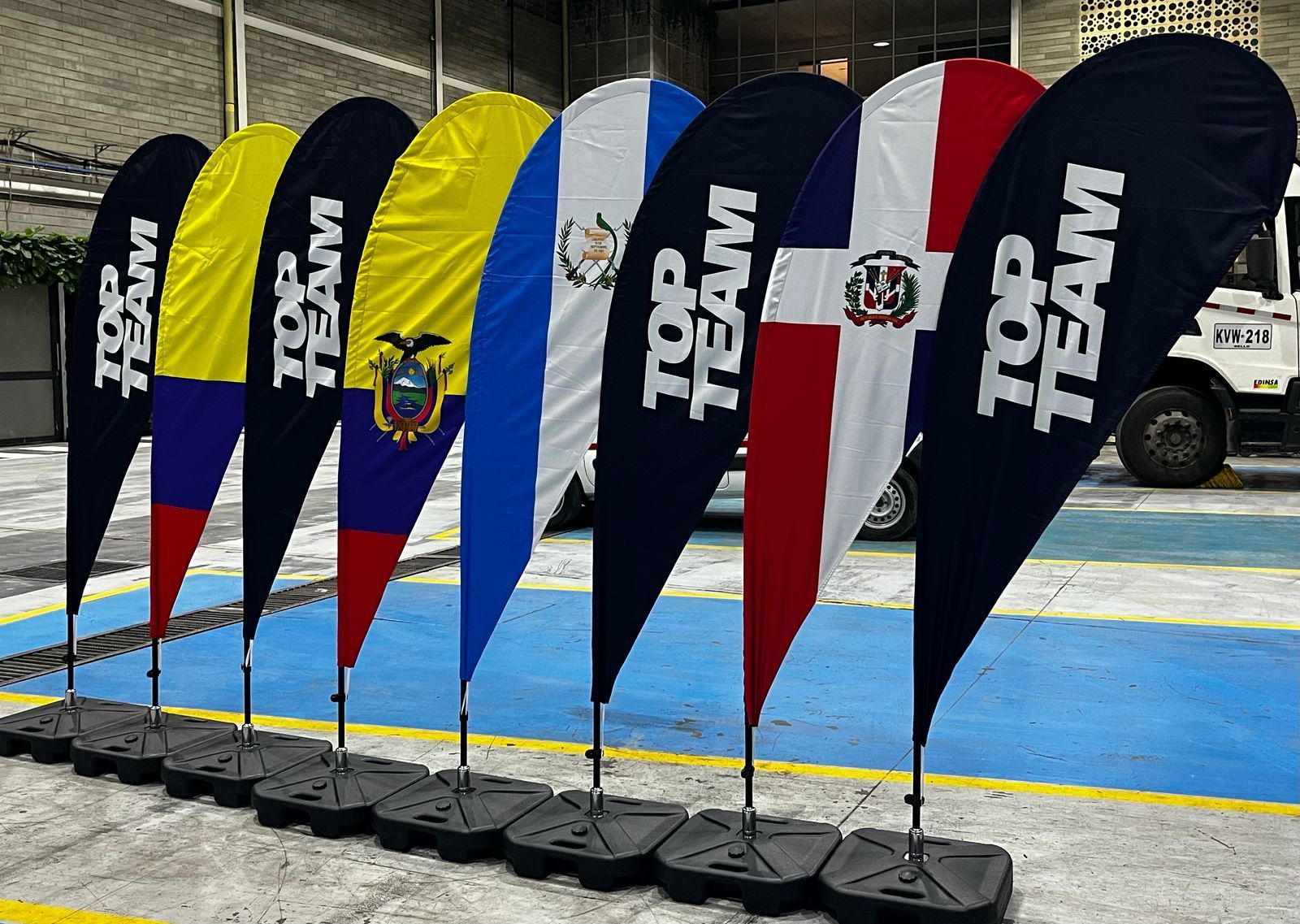 Una fila de banderas de los mejores equipos están alineadas en un estacionamiento