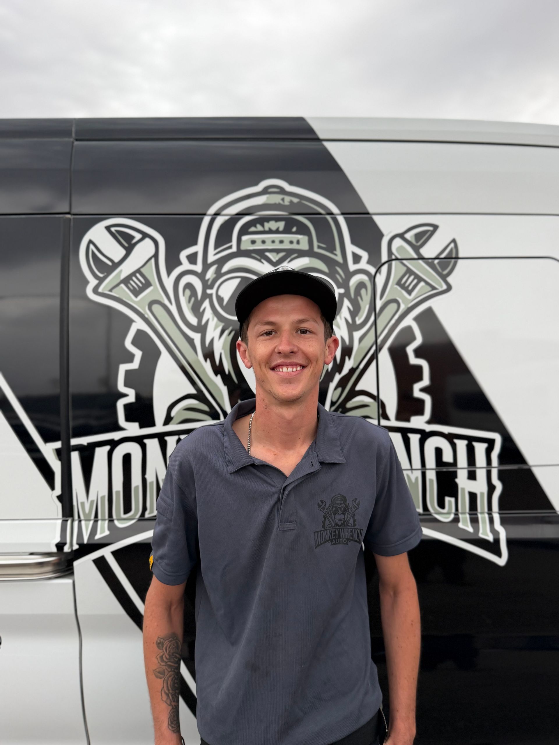 Man in gray polo and cap stands in front of a mobile repair truck logo.