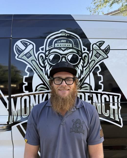 Man standing before a van with a large monkey mechanic logo and “Monkey Wrench” text