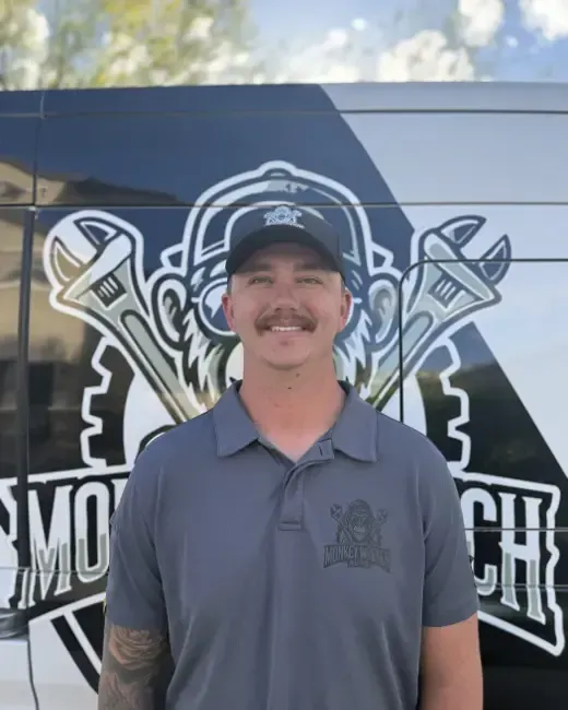 Man in gray polo and cap stands in front of a mobile repair truck logo.