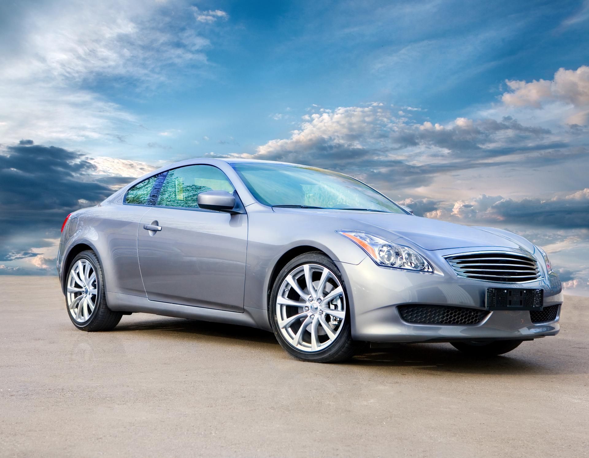 Silver coupe parked on a road under a cloudy sky
