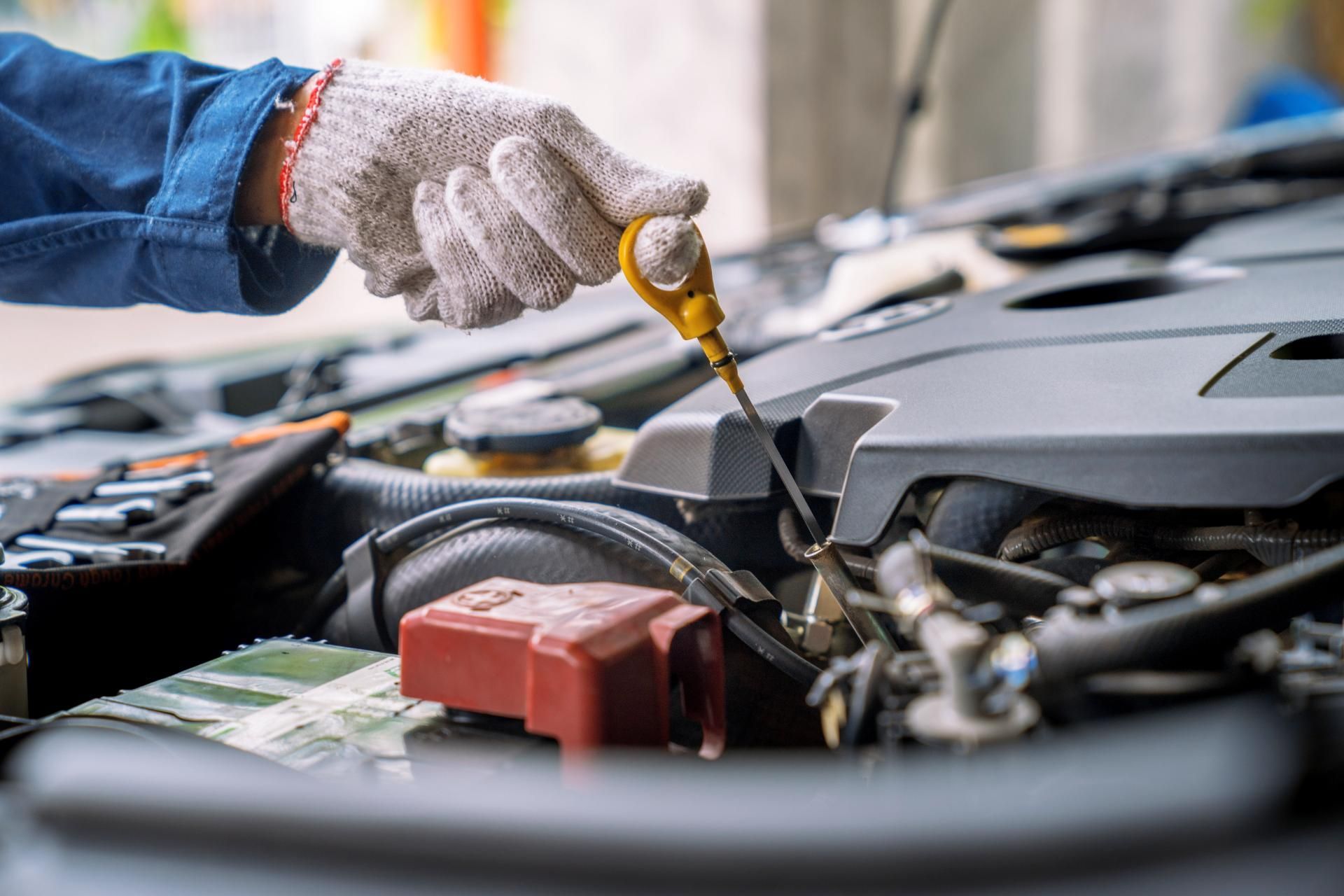 Gloved hand checking engine oil dipstick in a car engine bay
