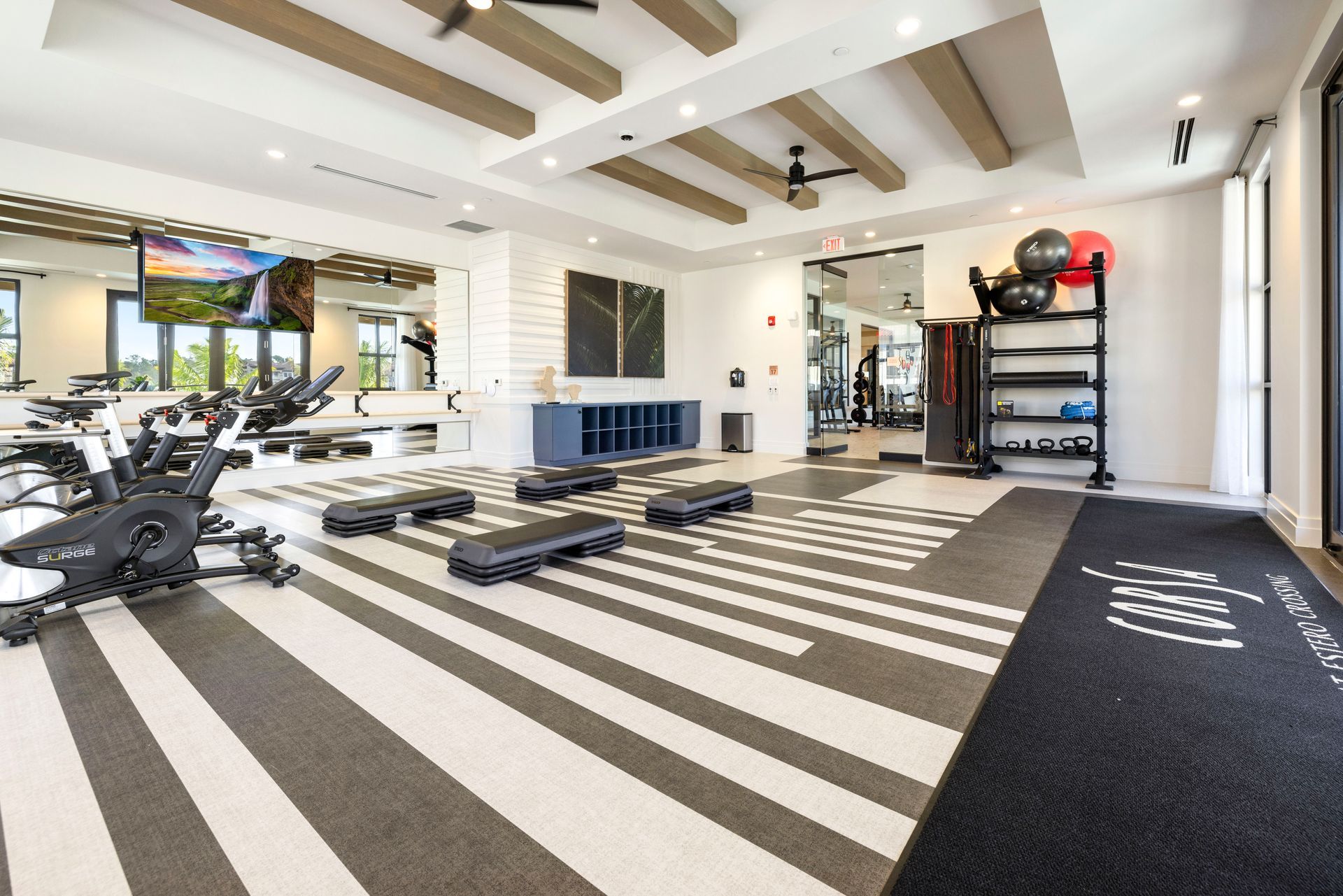 A large gym with a striped floor and a tv on the wall at Corsa at Estero Crossing.