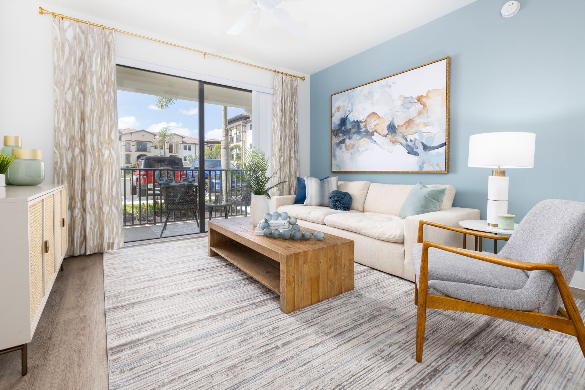 A living room with a couch , chair , coffee table and balcony at Corsa at Estero Crossing.
